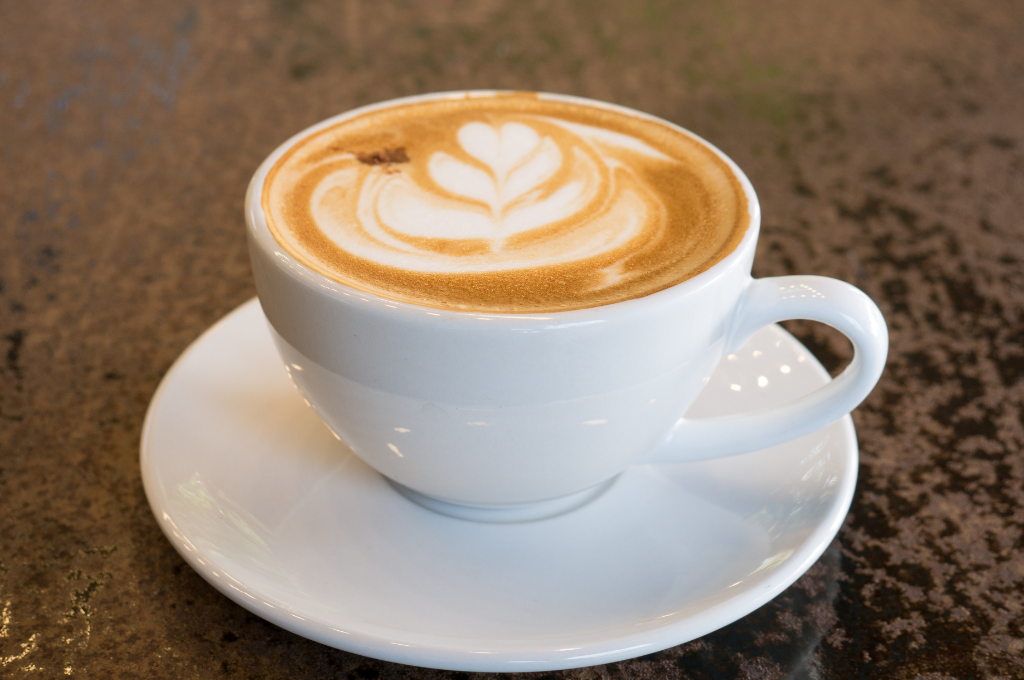 Eine weisse Tasse mit Cappuccino auf einem Tisch
